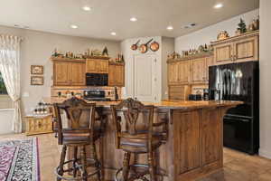 Kitchen with black appliances, light stone counters, recessed lighting, light tile patterned floors, and backsplash