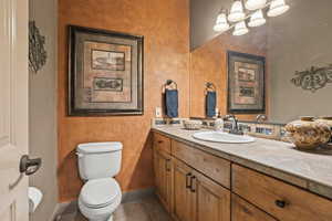 Bathroom with vanity, toilet, baseboards, and tile patterned flooring