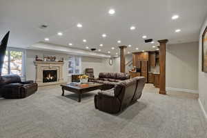 Living area with light colored carpet, recessed lighting, a fireplace, stairway, and baseboards