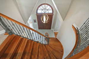 Foyer with high vaulted ceiling, stairway, baseboards, and wood finished floors