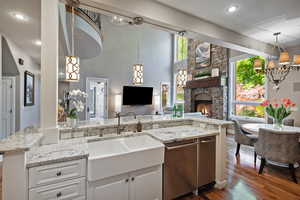 Kitchen featuring a sink, dishwasher, dark wood finished floors, open floor plan, and white cabinets