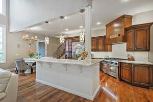 Kitchen with high quality appliances, a breakfast bar, baseboards, light wood-type flooring, and decorative backsplash