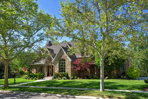 View of front of property featuring stone siding, a front lawn, and a chimney