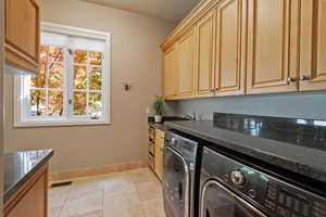 Laundry room featuring independent washer and dryer, baseboards, cabinet space, and light tile patterned floors