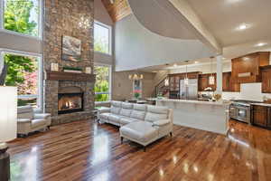 Living room with hardwood / wood-style floors, a chandelier, a fireplace, high vaulted ceiling, and recessed lighting