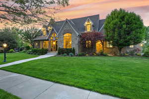 View of front of home featuring stone siding and a lawn