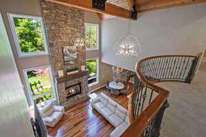 Living area featuring a chandelier, plenty of natural light, a fireplace, wood finished floors, and high vaulted ceiling
