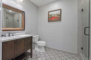 Full bath with toilet, vanity, a shower stall, baseboards, and tile patterned floors