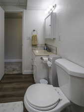 Bathroom with vanity, wood finished floors, toilet, and baseboards