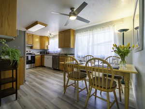 Kitchen with stainless steel appliances, a ceiling fan, light wood-style floors, and under cabinet range hood