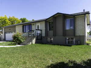 View of front of home with an attached garage, a front yard, and brick siding