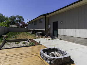Deck with an outdoor fire pit, a fenced backyard, and a garden