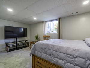 Bedroom with light carpet, a drop ceiling, and recessed lighting