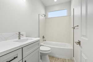 Bathroom with washtub / shower combination, light wood-style flooring, and vanity