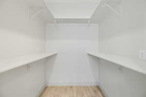 Walk in closet with light wood-type flooring