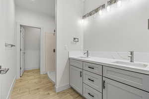 Bathroom featuring double vanity, a stall shower, and wood finish floors