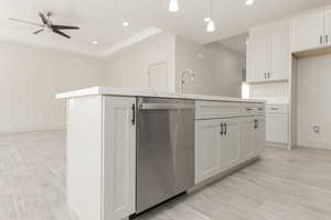 Kitchen featuring stainless steel dishwasher, a center island with sink, a ceiling fan, recessed lighting, and light countertops