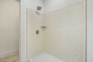Bathroom featuring tiled shower and wood finished floors