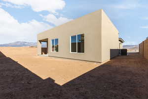 Back of property with a fenced backyard, central AC unit, and stucco siding
