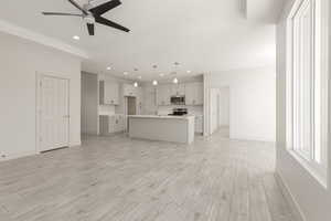 Kitchen with appliances with stainless steel finishes, open floor plan, a ceiling fan, recessed lighting, and baseboards