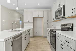 Kitchen with appliances with stainless steel finishes, recessed lighting, light stone countertops, wood finish floors, and decorative light fixtures