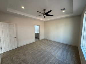 Unfurnished bedroom with a raised ceiling, dark colored carpet, a ceiling fan, and recessed lighting