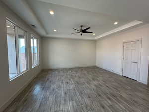 Unfurnished room with a raised ceiling, recessed lighting, dark wood-style flooring, and a ceiling fan