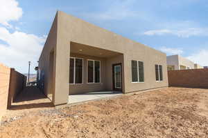Back of house with stucco siding and a patio