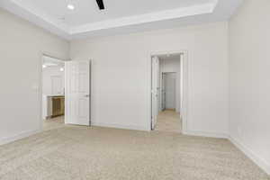 Unfurnished bedroom with light carpet, a tray ceiling, ceiling fan, and recessed lighting