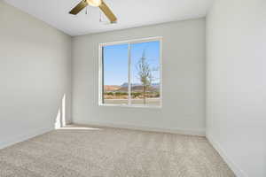Carpeted empty room featuring a mountain view and ceiling fan