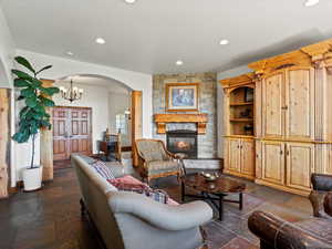 Living area viewing front entry, featuring slate flooring, arched details, stone fireplace
