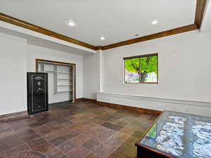 Lower primary bedroom featuring crown molding, baseboards, slate flooring, and closet.