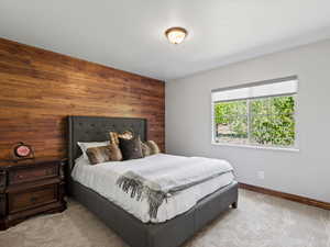 Carpeted bedroom featuring wooden walls