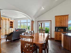 Open dining, kitchen, living area with vaulted ceilings and access to outdoor dining on covered deck