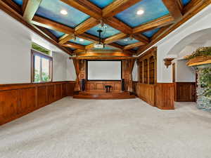 Carpeted home theater room featuring wainscoting, coffered ceiling, beam ceiling, recessed lighting, and a performance stage
