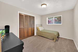 Carpeted bedroom featuring a closet, a textured ceiling, and baseboards
