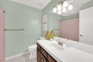 Bathroom featuring toilet, vanity, baseboards, and tile patterned flooring