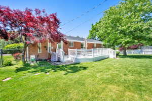 Rear view of house featuring a trampoline, a wooden deck, and brick siding