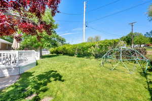 View of grassy yard featuring a deck