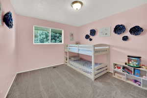 Carpeted bedroom featuring a textured ceiling and baseboards