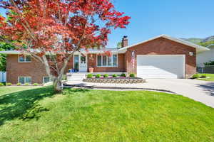 View of front of house with a chimney, brick siding, and driveway