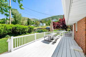 Deck with a mountain view, a lawn, and outdoor dining area