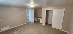 Bedroom featuring baseboards, light colored carpet, a closet, and a textured ceiling