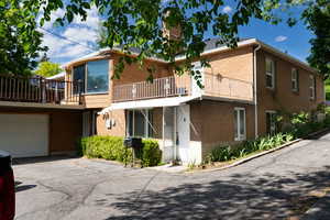 View of front of house featuring driveway, brick siding, a balcony, and a garage