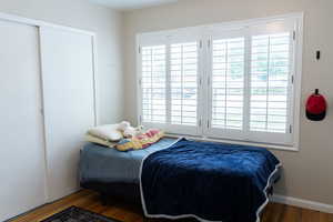 Bedroom featuring wood finished floors, multiple windows, and baseboards