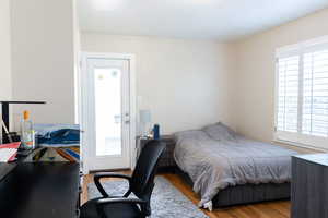 Bedroom with multiple windows, wood finished floors, and an office area