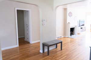 Hall with light wood-style floors, arched walkways, and baseboards