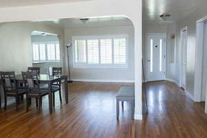 Dining area with plenty of natural light, dark wood-type flooring, arched walkways, and baseboards