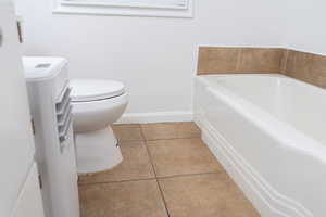 Full bathroom with a bath, tile patterned flooring, toilet, and baseboards