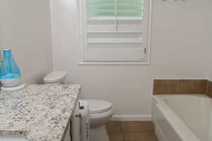 Bathroom with a  tub, tile patterned floors, vanity, toilet, and baseboards